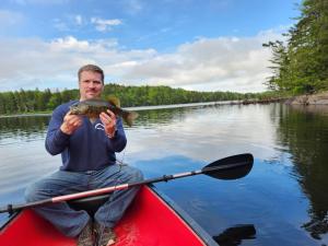 a man sitting in a kayak holding a large fish at Twin Bucks Cabin in Whiting