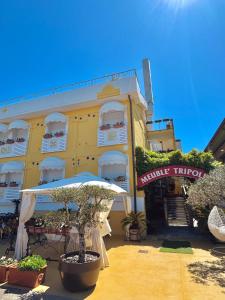a yellow building with an umbrella in front of it at Meublè Tripoli in Grado