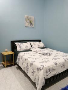 a bedroom with a bed with a black and white comforter at IBY II Homestay in Ketereh