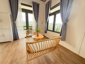 a living room with a table and chairs and windows at Mây HomeStay in Da Lat +30 photos