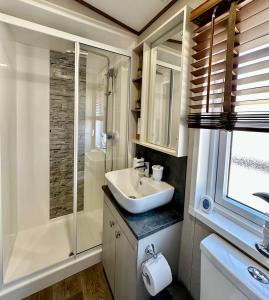 a bathroom with a sink and a shower at Exclusive Lakeside Holiday Lodge with Hot tub and Private Fishing Peg at Tattershall Lakes in Tattershall +15 photos