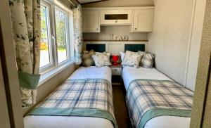 two beds in a small room with a window at Exclusive Lakeside Holiday Lodge with Hot tub and Private Fishing Peg at Tattershall Lakes in Tattershall