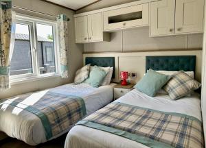 a bedroom with two beds and a window at Exclusive Lakeside Holiday Lodge with Hot tub and Private Fishing Peg at Tattershall Lakes in Tattershall