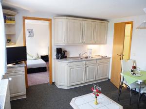 a kitchen with white cabinets and a room with a bed at Zimmervermietung Karsch in Neustadt in Sachsen