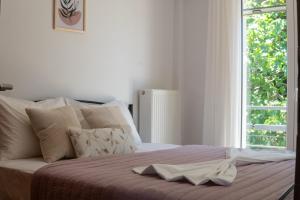 a white bed with a robe on it with a window at Aura 2 Apartment in Vathý