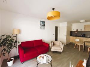 a living room with a red couch and a table at DOMITYS LA CALYPSO in Brest