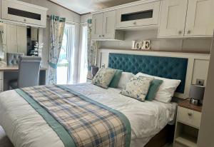 a bedroom with a large bed with a blue headboard at Exclusive Lakeside Holiday Lodge with Hot tub and Private Fishing Peg at Tattershall Lakes in Tattershall
