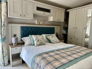 a bedroom with a large bed with a blue headboard at Exclusive Lakeside Holiday Lodge with Hot tub and Private Fishing Peg at Tattershall Lakes in Tattershall