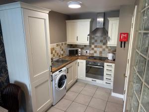 a kitchen with white cabinets and a washer at Harbour View Holiday Apartment in Donaghadee