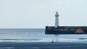 a lighthouse in the ocean with a beach with a lighthouse at Harbour View Holiday Apartment in Donaghadee