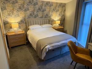 a bedroom with a bed and two night stands with lamps at Harbour View Holiday Apartment in Donaghadee