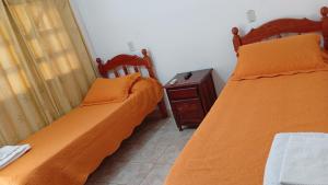 two beds in a small room with a night stand at Ragas in Palma Sola