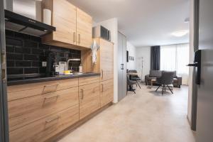 a kitchen with wooden cabinets and a living room at AN-Living Apartments in Emsbüren
