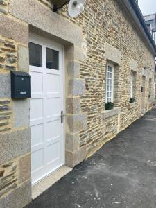 a white garage door on a brick building at Charmant maison in Pontorson