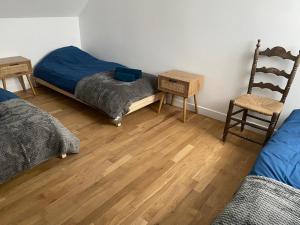 a bedroom with two beds and a chair and wooden floors at Charmant maison in Pontorson