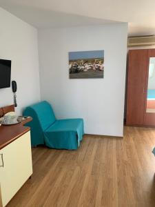 a room with a blue chair and a television at Marina House in Sulina