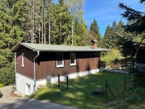 a small house with a grass yard in front of it at Ferienhaus mit Sauna am Waldrand in Friedrichroda