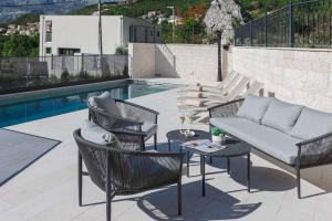 a patio with a couch and chairs next to a pool at Boutique Villa Levante in Blizikuće