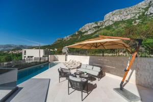 a patio with a table and an umbrella next to a pool at Boutique Villa Levante in Blizikuće