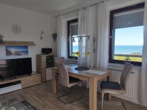 a dining room with a table and chairs and a television at Ferienwohnung mit Meerblick, 2 Schlafzi, Box- Bett, Süd- Balkon, eig, Parkplatz, Glasfaser in Dahme