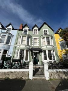 a green and yellow house with a black fence at The Westbourne Guest House in Llandudno