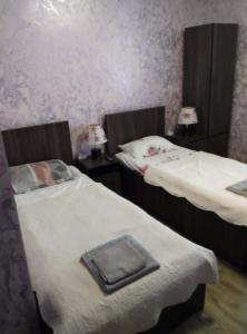 two twin beds in a room with purple wallpaper at Hotel Pagio in Chaisubani