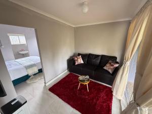 a living room with a black couch and a red rug at Vumasky self catering in Ladysmith