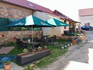 a patio with tables and umbrellas in a yard at Krčma na statku in Zásmuky
