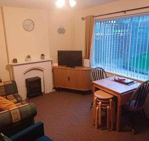 a living room with a table and a television and a fireplace at The Orange room in Lincolnshire