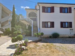 a large white house with a staircase in front of it at Apartment Ruzmarin in Šilo