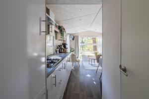 a kitchen with white cabinets and a counter top at Sfeervol boshuisje op de Veluwe Vossenberg in Nunspeet