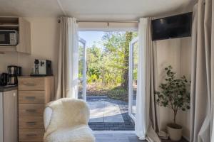 a living room with a chair and a sliding glass door at Sfeervol boshuisje op de Veluwe Vossenberg in Nunspeet