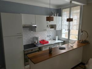 a kitchen with white cabinets and a wooden counter top at Maison Quebec in Bernières-sur-Mer
