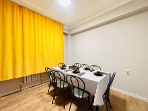a dining room with a table with chairs and a yellow curtain at Гостевой Хаб у Сайрана 8 спальных мест у автовокзала in Almaty