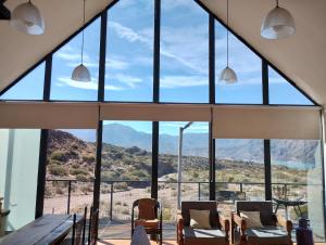 a room with large windows and a table and chairs at Cabaña San Charbel in Potrerillos