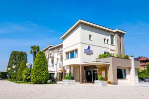 a large white building with trees in front of it at Hotel Tre Vele in Sirmione