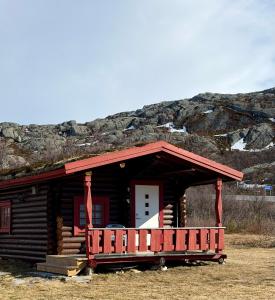 a log cabin with a porch and a mountain at Grasbakken hytteutleie in Nesseby