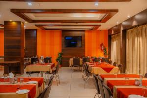 a restaurant with tables and chairs and a flat screen tv at Hotel Prince Residency, Bhuj in Bhuj