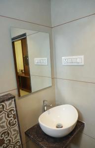 a bathroom with a white sink and a mirror at Sapphire Suites in Navi Mumbai