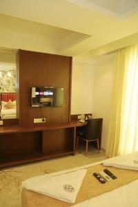 a hotel room with a bed and a desk with a television at Sapphire Suites in Navi Mumbai