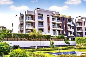an apartment building with a garden in front of it at Modern chic rooftop studio in Sheikh Zayed