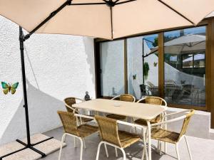 a table with chairs and an umbrella on a patio at Casa Etxetxoa - Calpe in Ifach