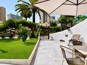 a patio with an umbrella and a green lawn at Casa Etxetxoa - Calpe in Ifach