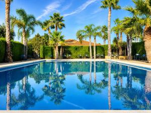 a swimming pool with palm trees and a house at Casa Etxetxoa - Calpe in Ifach