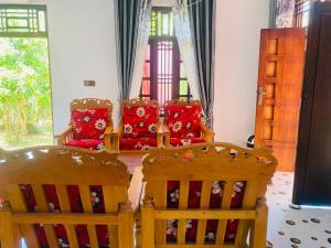 two wooden chairs sitting in a room with red pillows at MOMS Villa in Arugam Bay