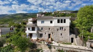 a house on a hill with people walking in front of it at Guri Guesthouse in Gjirokastër