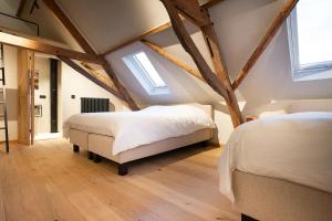 two beds in a attic bedroom with wooden beams at Herberg 't Molenhuis in Vichte