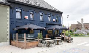 a blue building with tables and chairs and umbrellas at Herberg 't Molenhuis in Vichte