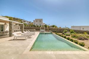 a swimming pool with chaise lounge chairs next to a house at Villa Ariadni Paros in Isterni