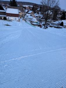 a snow covered road with a town in the background at Zimmervermietung Karsch in Neustadt in Sachsen